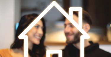 man and woman smiling behind home outline