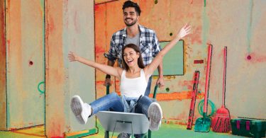 man with wheelbarrow and woman renovating a home