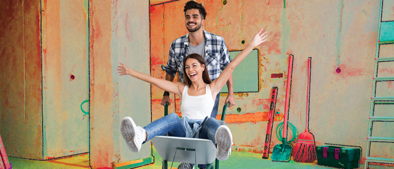 man with wheelbarrow and woman renovating a home