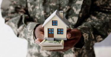 veteran holding a home with money underneath