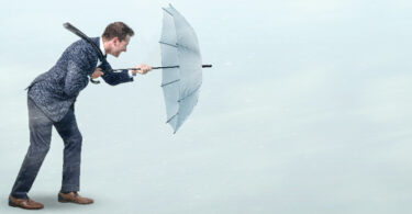 man fighting wind with umbrella
