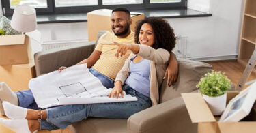 couple on couch looking at blueprints