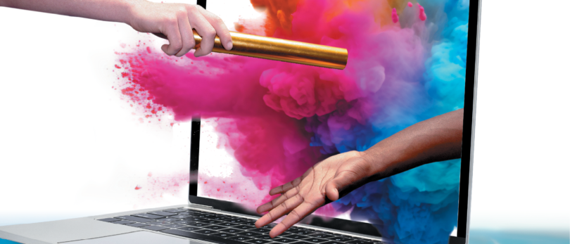 hands passing baton through computer with colorful dust